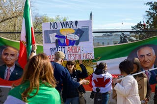 A woman holds up a sign featuring an image of Reza Pahlavi, son of the last shah of Iran, and US President Donald Trump as demonstrators march toward the White House during a rally in support of Iranians' fight for freedom, in Washington, DC, on March 29, 2026. The event, organized by DCProtests4Iran, brought together members of the Iranian diaspora from the Washington, DC metropolitan area and surrounding states. (Photo by Amid FARAHI / AFP via Getty Images)
